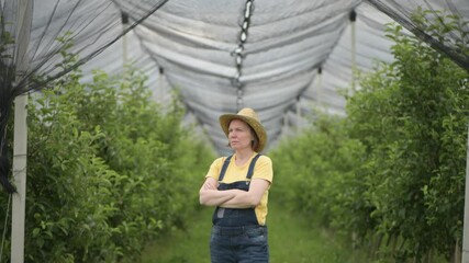 Portrait of female farmer posing in apple fruit orchard