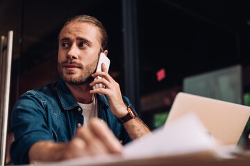 selective focus of businessman looking away and talking on smartphone