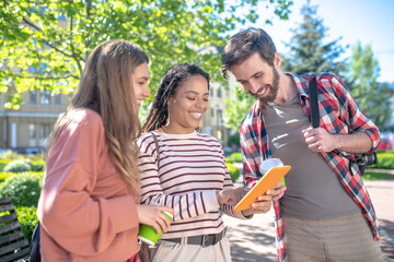 girl showing tablet screen to girlfriend and boyfriend