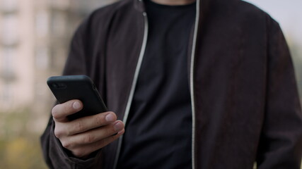 Man hand touching phone screen. Attractive guy speaking cellphone outdoors.