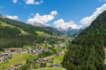 Fototapeta na wymiar The stunning Alpine village of Ortisei with blue sky and white fluffy clouds, an awesome view of the majestic Dolomites, Northern Italy, Europe