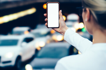 Cropped back view of hipster girl holding digital telephone with copy space area for your internet website on bokeh background.Young woman with modern cellular device with mock up area