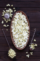 Fresh and dried jasmine flowers on a dark wooden table. Harvesting flowers for flavoring tea. Jasmine flowers in an oval wooden dish and retro tea strainers.