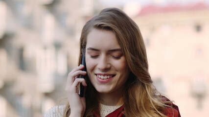 Smiling girl speaking phone on street. Happy woman using phone outdoors