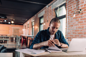 selective focus of concentrated businessman looking at notebook near laptop