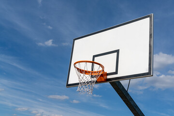 isolated view of a basketball hoop and backboard under an expressive blue sky