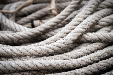 Fototapeta na wymiar Mooring rope old frayed boat then piled on the floor. Ship or rock climbing tackle.