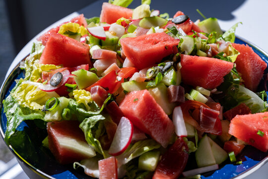close up view of a healthy vegetable and watermelon salad with bits of bacon
