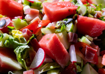 close up view of a healthy vegetable and watermelon salad with bits of bacon