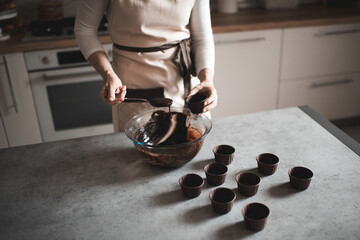 Woman making chocolate batter for muffins at home in kitchen closeup. Selective focus. Top view.