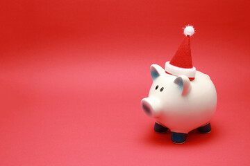 Ceramic piggy bank in Santa Clause hat isolated on red background with copy space 
