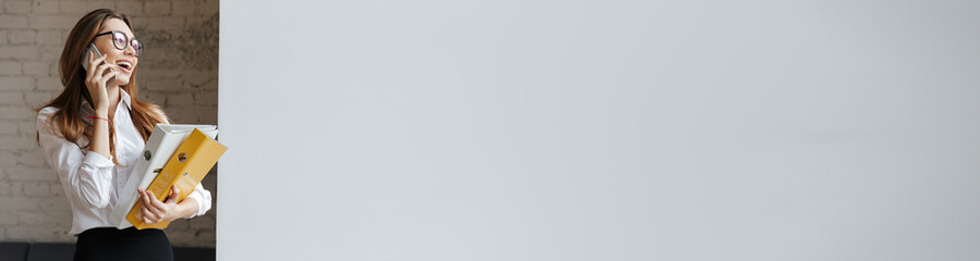 Young happy business woman holding folders looking aside.