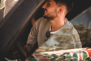 Dettaglio dal finestrino della sua automobile di un giovane ragazzo attraente mentre è in viaggio per le vacanze estive