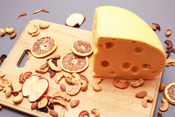 Snack cheese with nuts mix and dry fruits on wooden cutting board isolated on gray background