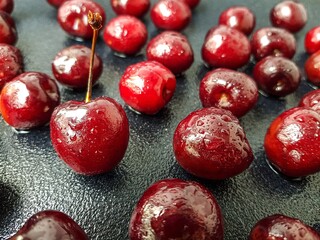 Juicy ripe cherry with drops of water after washing on a dark background.