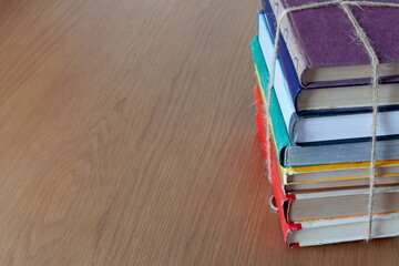 a stack of books tied with a rope on a wooden table, near free space for text