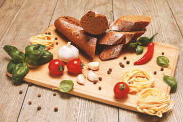 close up view on bread with red pepper,garlic,basil,spaghetti,sunflower oil and rosemary on wooden board.