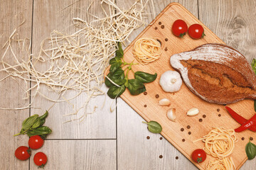 close up view on bread with red pepper,garlic,basil,spaghetti,sunflower oil and rosemary on wooden board.
