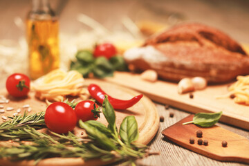 close up view on bread with red pepper,garlic,basil,spaghetti,sunflower oil and rosemary on wooden board.