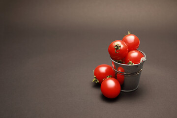 close up view of small toy bucket with fresh cherry tomatoes with copy space