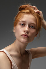 Dreams. Fashion portrait of beautiful redhead woman isolated on grey studio background. Concept of...