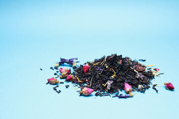 Fragrant herbal dry leaf tea with fruits and petals on blue background