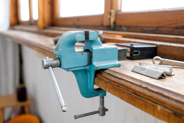 A vise is attached to the edge of the window sill. Metal tool