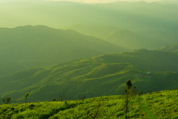 Sunset and mountains interspersed with green grass