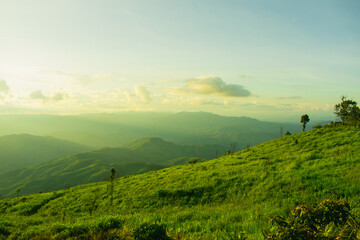 Sunset and mountains interspersed with green grass