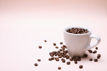 Cup of coffee beans inside isolated on a light pink background with copy space.