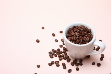 Cup of coffee beans inside isolated on a light pink background with copy space.