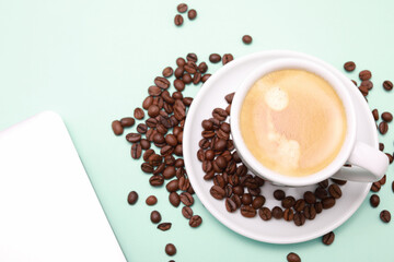 White cup of coffee, around beans, note book and pen isolated color background.