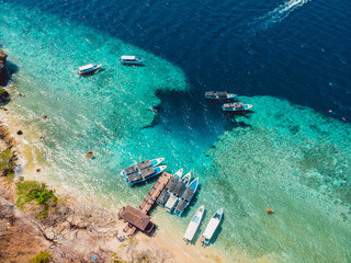 Touristic boats near the pier in blue transparent ocean at Menjangan island.