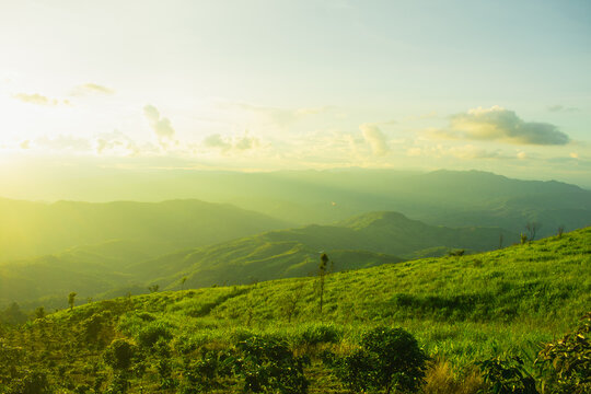 Sunset and mountains interspersed with green grass