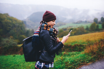Young female wanderer using gps navigation on mobile phone to find the right way during adventure...