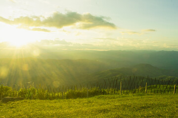 Sunset and mountains interspersed with green grass