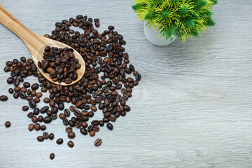 Coffee beans in wooden spatula on wooden table 
