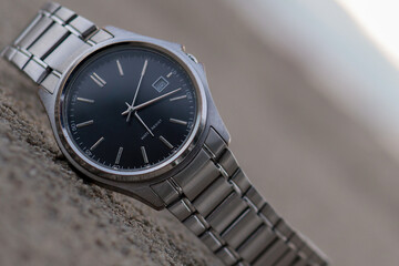 The watch (Close-up) is put on the sand. Natural blurred background