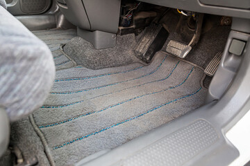 Gray textile car mat in the interior of a Japanese car with three pedals - gas, brake and clutch in...