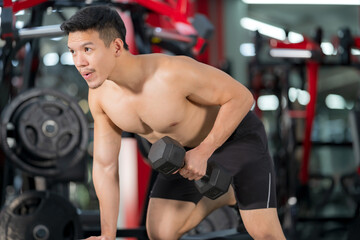 Naklejka na ściany i meble Sporty man training with dumbbell in gym