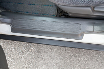 Open passenger door of a white Japanese crossover with a black rubber trim on the doorstep after...