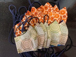 Pile of cloth face masks that have been hand sewn and ready to be donated with two circular fabric designs