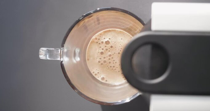 Espresso leaving the coffee maker and falling into a glass cup, shot in plong&eacute;e
