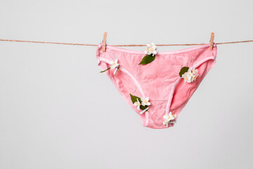 Woman's pink underwear with flowers on clothesline, concept content for feminist blog, poster about women's health