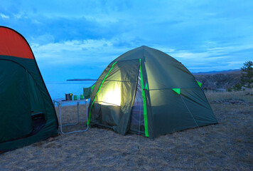 Baikal Lake on a summer evening. Tourist tent on the shores of the Small Sea Strait. Summer travel to Olkhon Island