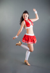young attractive woman in red cheerleader costume poses at camera in studio