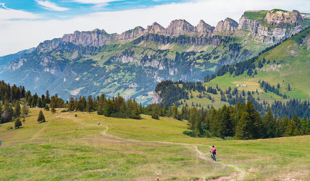 active senior woman riding her electric mountain bike below the seven summits of Churfirsten in Canton St. Gallen, Switzerland, landscape