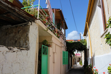Fototapeta na wymiar A very narrow street of a Cypriot village with green Windows and gates. Cyprus.