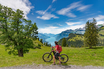 active senior woman riding her electric mountain bike below the seven summits of Churfirsten,...