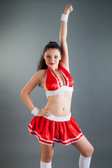 closeup beautiful slim brunette girl in red cheerleader costume poses at camera
